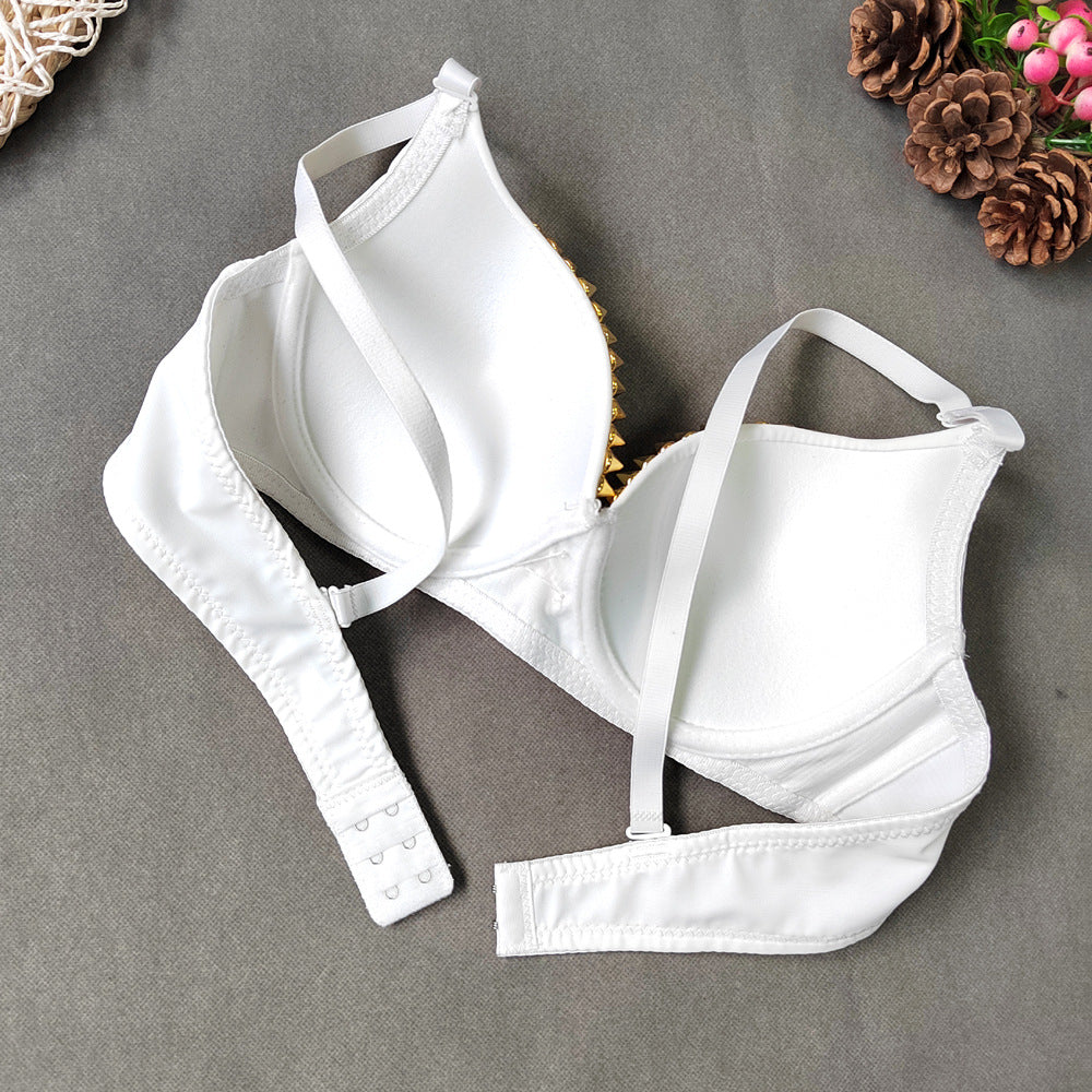White bralette with thin straps on a gray surface with decorative elements.