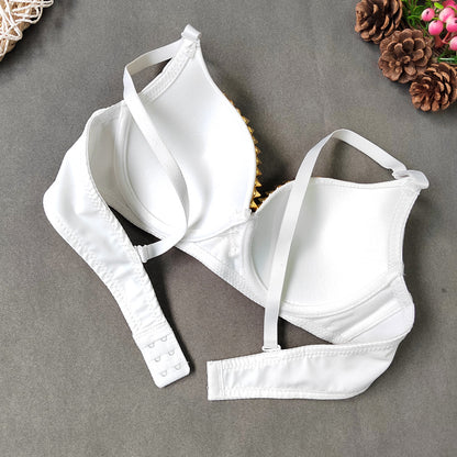 White bralette with thin straps on a gray surface with decorative elements.