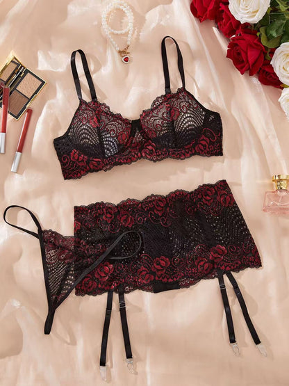 Black lace lingerie set on a soft fabric background with makeup and flowers.