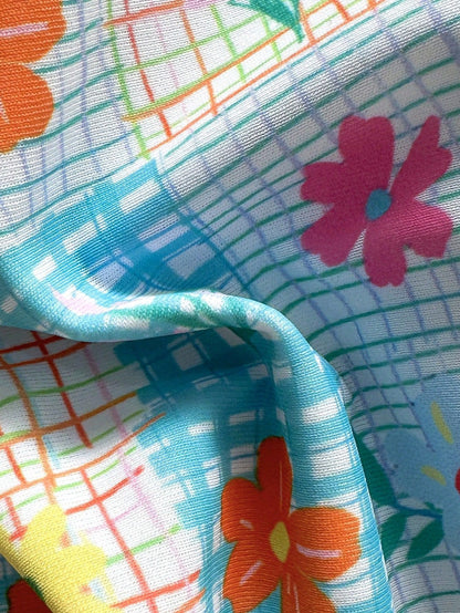 Close-up of colorful fabric with floral patterns and grid designs.