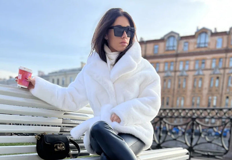 Woman in a white fur coat sitting on a bench holding a coffee cup, with a cityscape in the background.