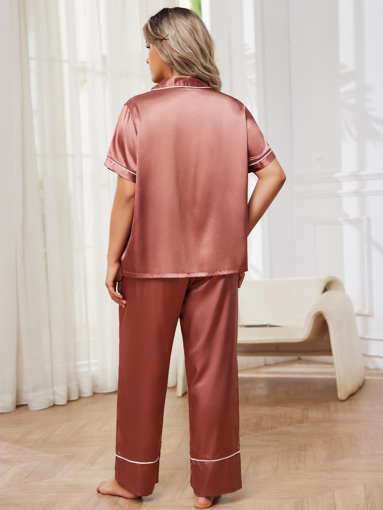 Woman wearing pink satin pajamas standing in a room with white curtains.