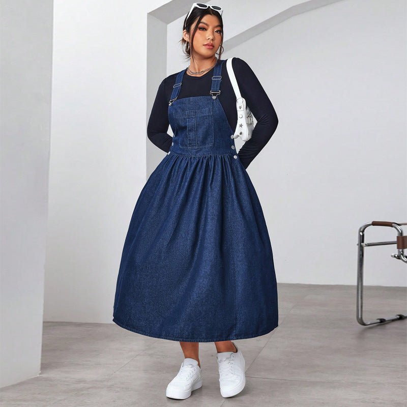 Woman wearing a blue denim dress over a black top in a minimalistic setting.