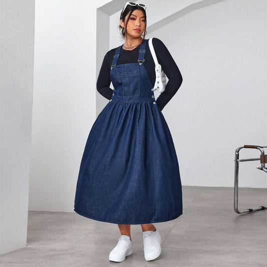 Woman wearing a blue denim dress over a black top in a minimalistic setting.