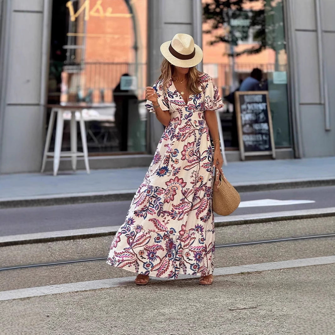 Woman in a floral dress and straw hat walking on a street.