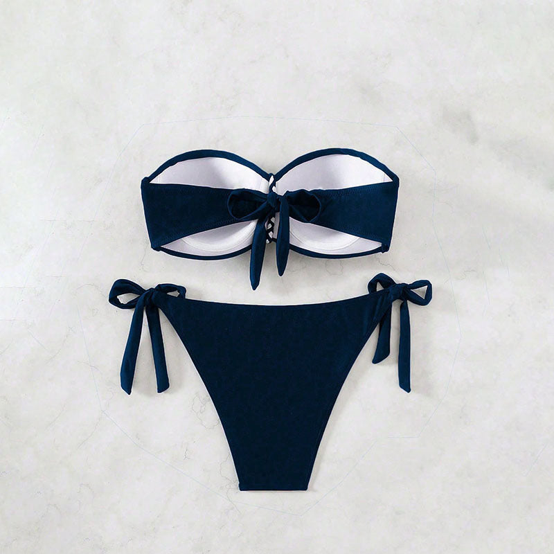 Navy blue bikini set with white trim on a light gray background