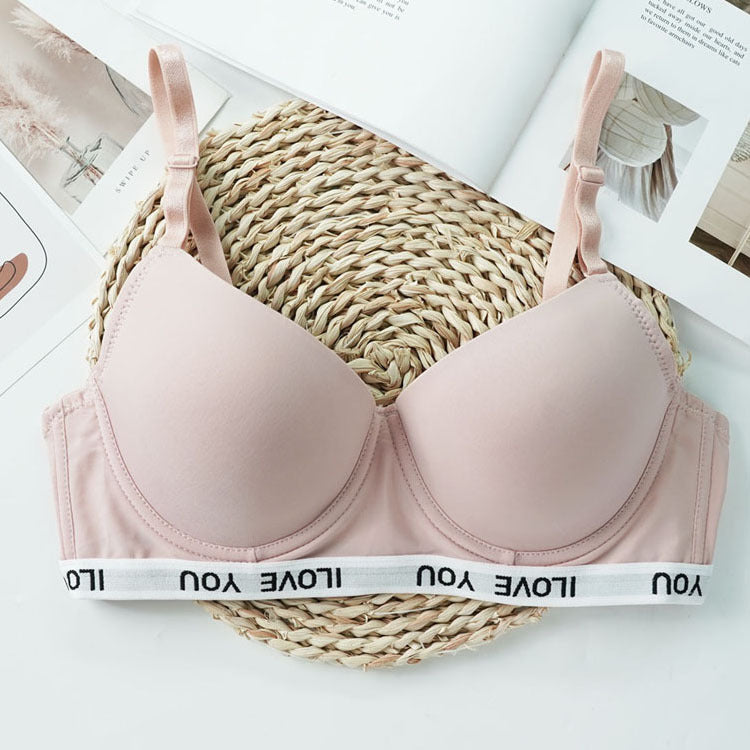 Pink bra on a woven mat with 'I Love You' band, placed on a magazine
