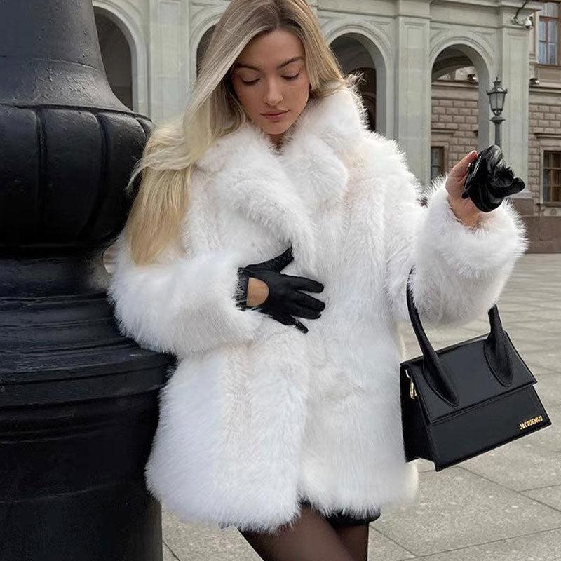 Woman in a white fur coat holding a black handbag on a city street.