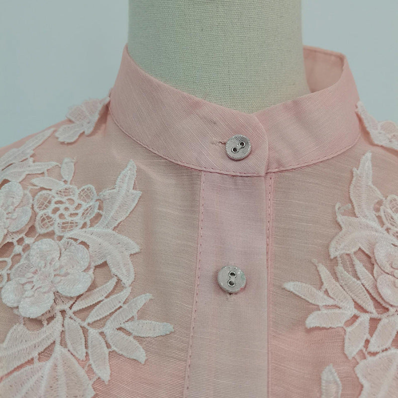 Pink blouse with lace details on a mannequin against a plain background