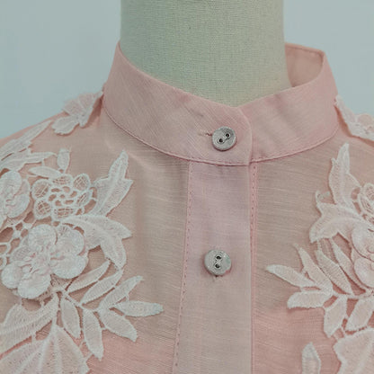 Pink blouse with lace details on a mannequin against a plain background
