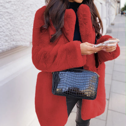 Person wearing a red coat holding a phone and a blue handbag on a city street.