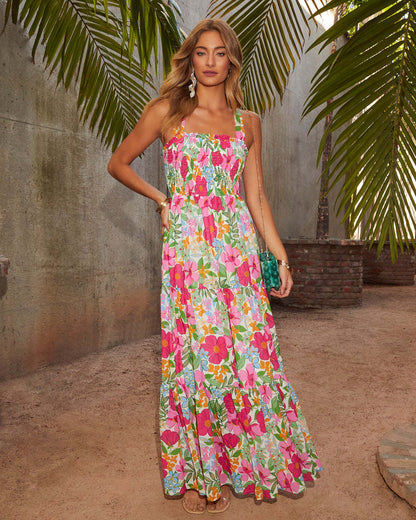 Woman wearing a floral dress standing outdoors with palm leaves in the background