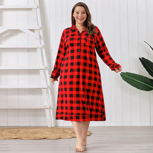 Woman wearing a red and black checkered dress standing in a room with a white wall and wooden floor.