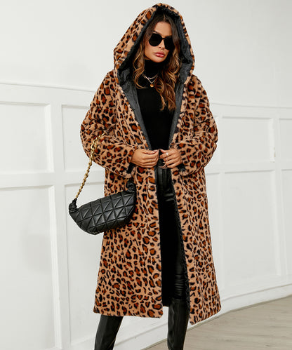 Person wearing a leopard print coat with a black quilted handbag against a white wall.