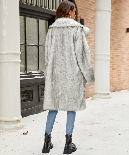 Person wearing a gray fur coat standing in a snowy urban setting.