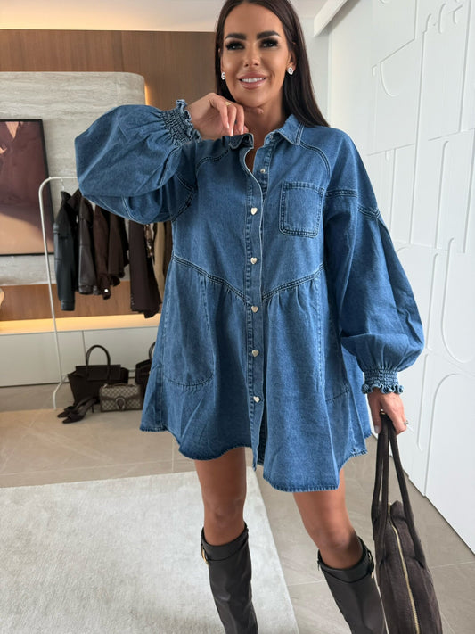 Woman wearing a blue denim dress in a room with a mirror and clothing rack. Women wearing casual long sleeve button denim dress with kurti