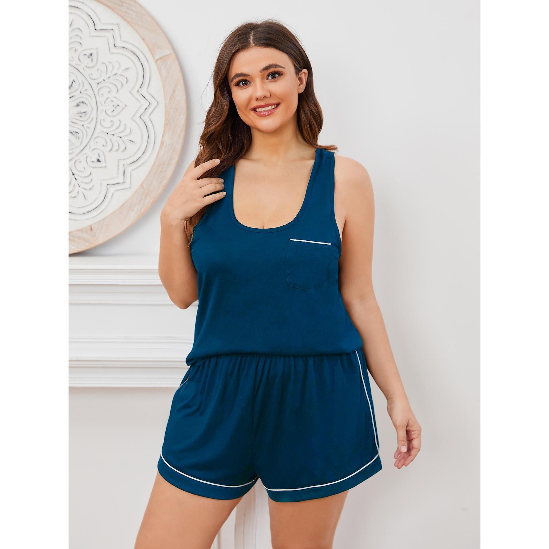 Woman wearing a blue tank top and shorts set against a white wall.