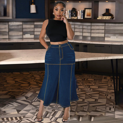 Woman wearing a black top and blue denim skirt standing in a modern interior setting.