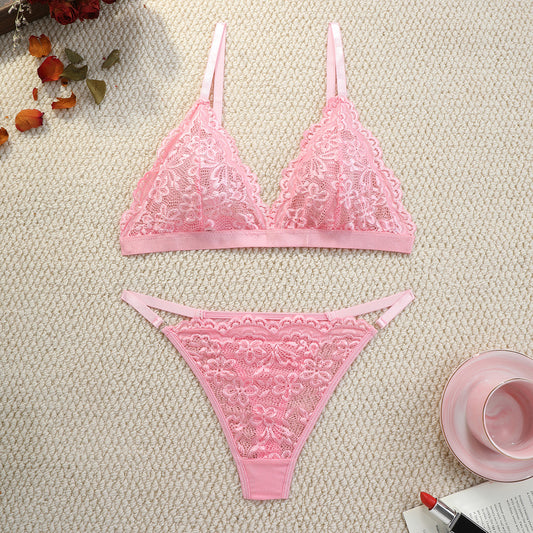 Pink lace lingerie set on a textured surface with decorative elements.