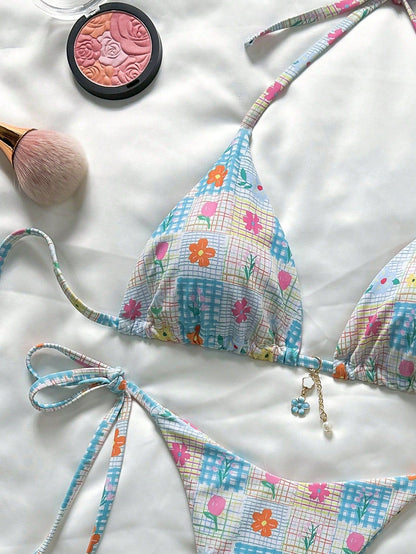 Colorful bikini with floral pattern on a white surface, accompanied by makeup items.
