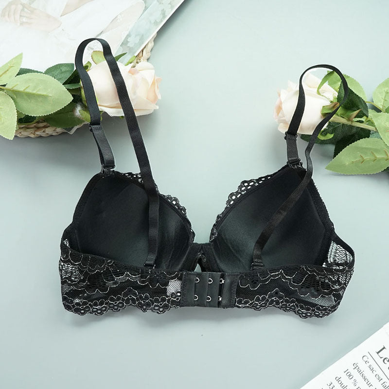 Black lace bra on a light blue background with greenery
