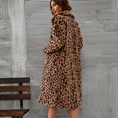 Woman wearing a leopard print coat standing against a textured wall.