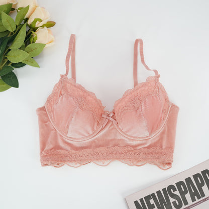 Pink lace bra on a white surface with flowers and newspaper in the background