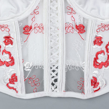 White lace garment with red floral embroidery on a gray background