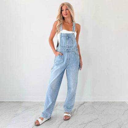 Woman wearing light blue denim overalls against a white background Women autumn tooling denim suspender pants in washed blue style