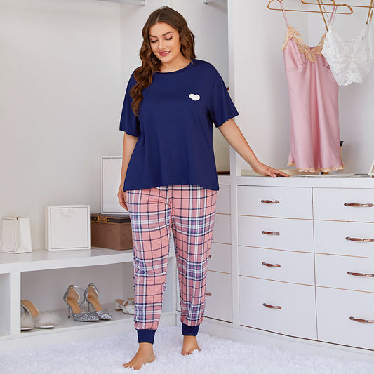 Woman wearing navy blue top and pink plaid pants in a bedroom setting.
