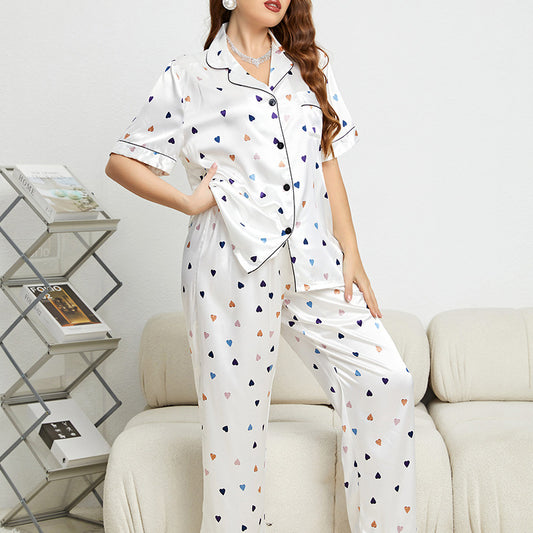 Woman wearing a white pajama set with colorful heart patterns, sitting on a couch.
