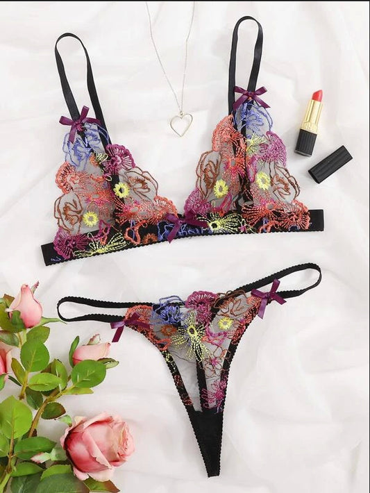 Decorative lingerie set with floral patterns on a white background, accompanied by flowers and lipsticks.