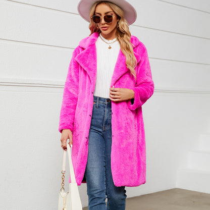 Woman wearing a bright pink coat, white top, blue jeans, and a white hat against a light background.