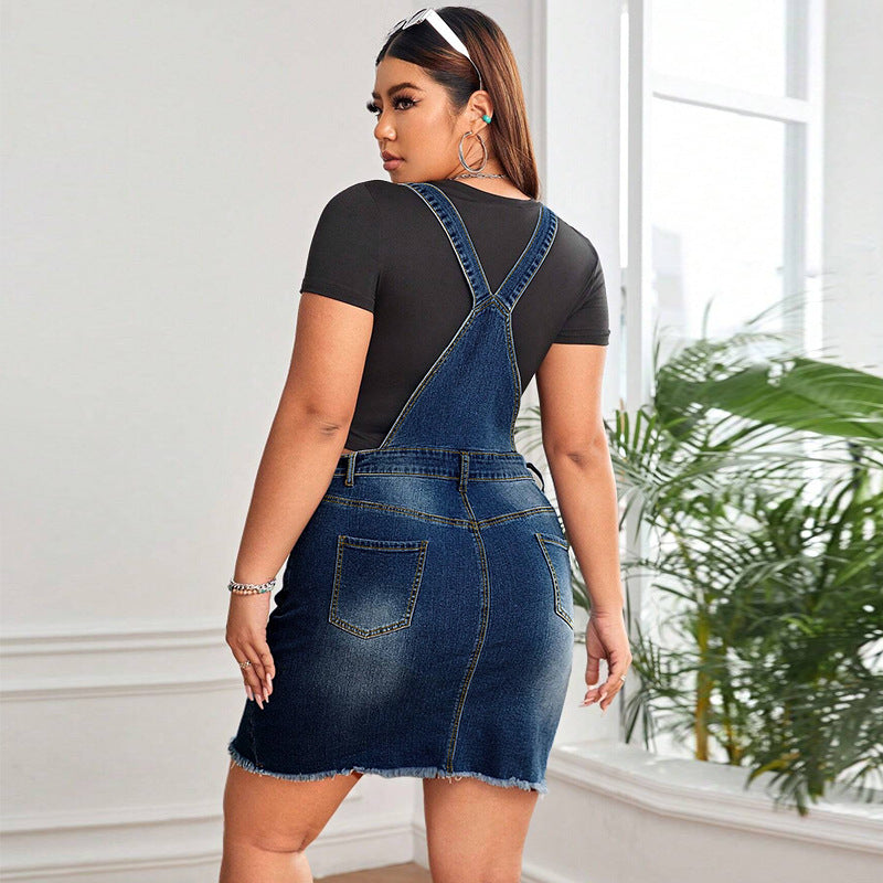 Woman wearing a denim pinafore dress with a black top indoors.