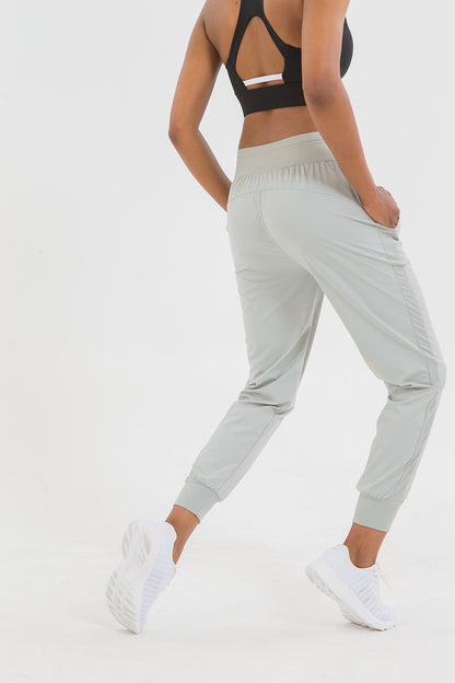 Person wearing light gray jogger pants and a black sports bra on a white background