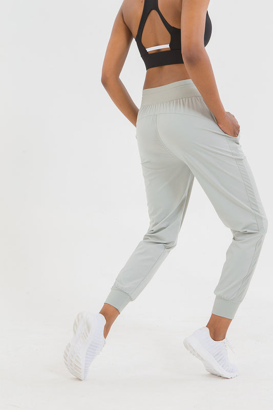 Person wearing light gray jogger pants and a black sports bra on a white background