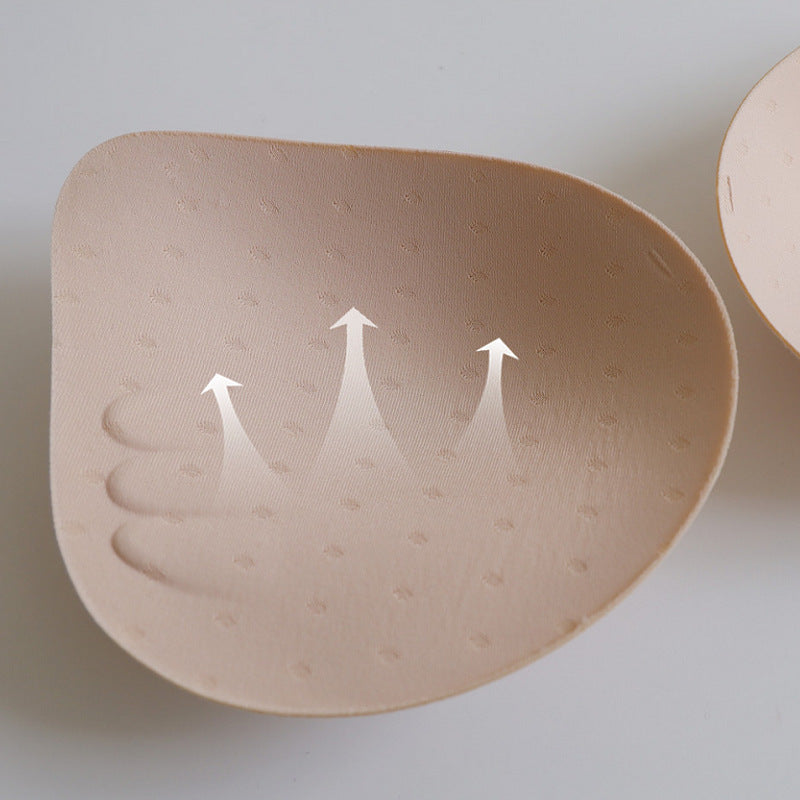 Beige silicone bra pad with arrows indicating direction on a light gray background
