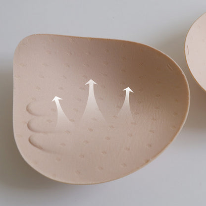 Beige silicone bra pad with arrows indicating direction on a light gray background