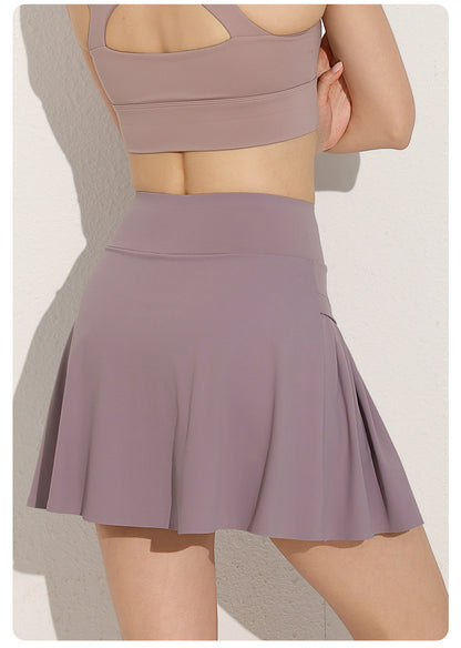 Person wearing a mauve sports bra and skirt set on a neutral background