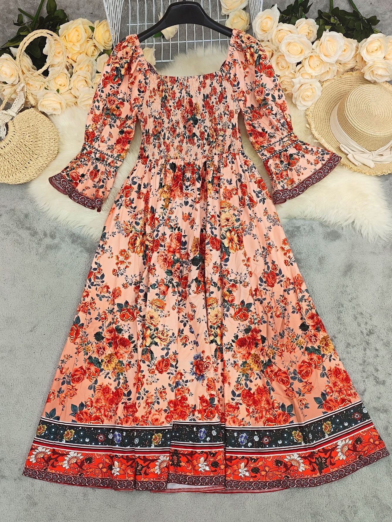 Floral dress with bell sleeves on a textured surface with decorative items.