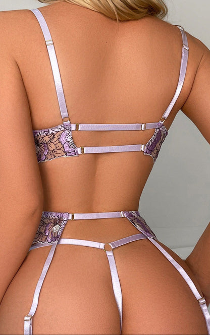 Person wearing a strappy, floral-patterned lingerie set against a neutral background
