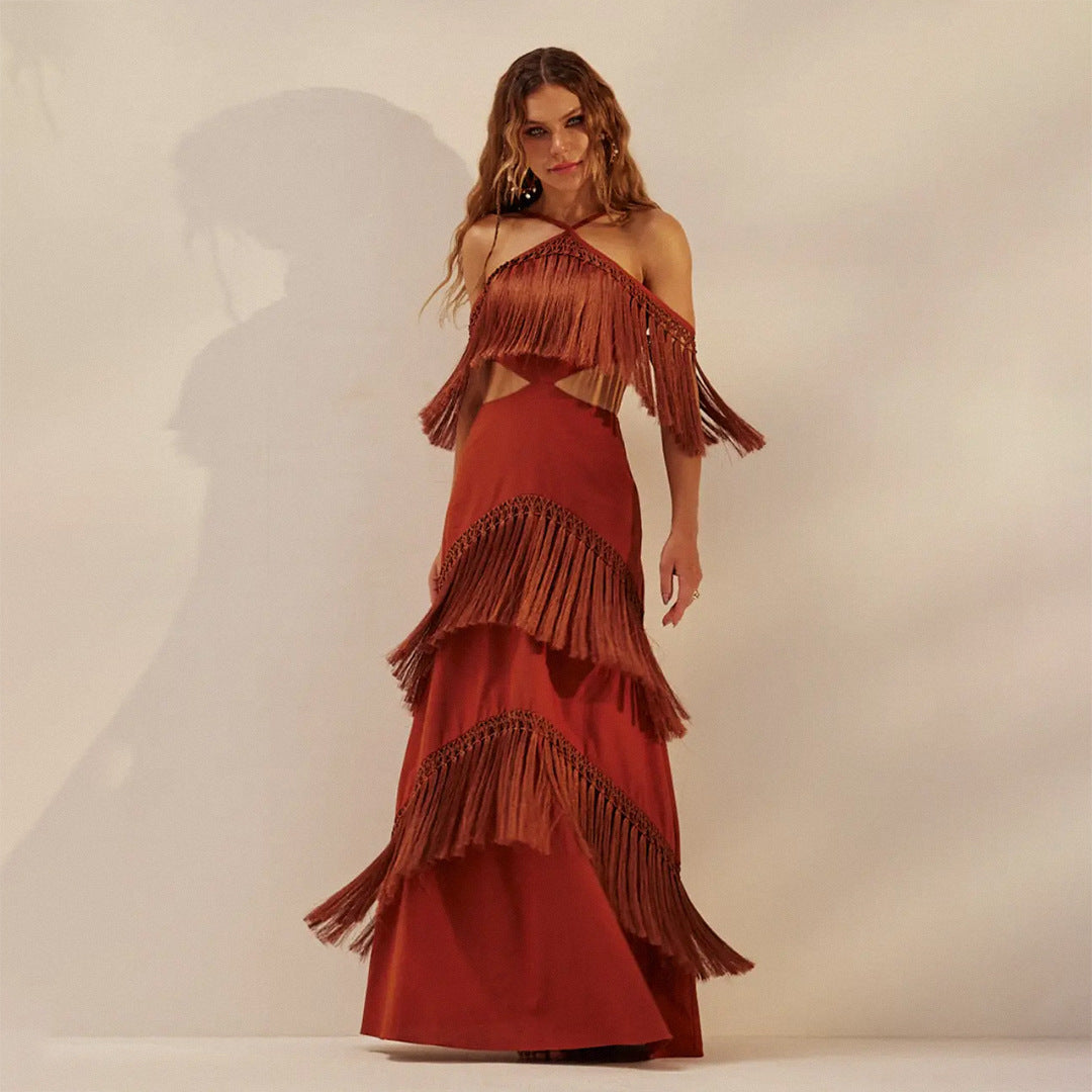 Woman wearing a long, tiered red dress with fringe details against a plain background