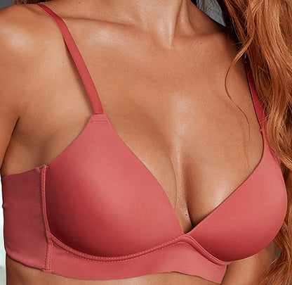 Woman wearing a pink bra against a neutral background