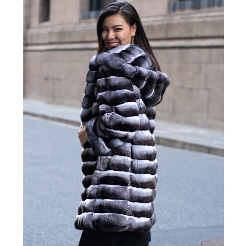 Woman wearing a long fur coat on a city street.