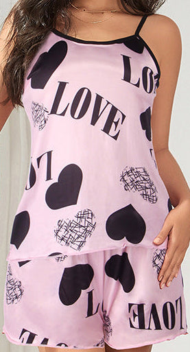 Woman wearing a pink romper with 'LOVE' and heart patterns in a stylish interior setting.