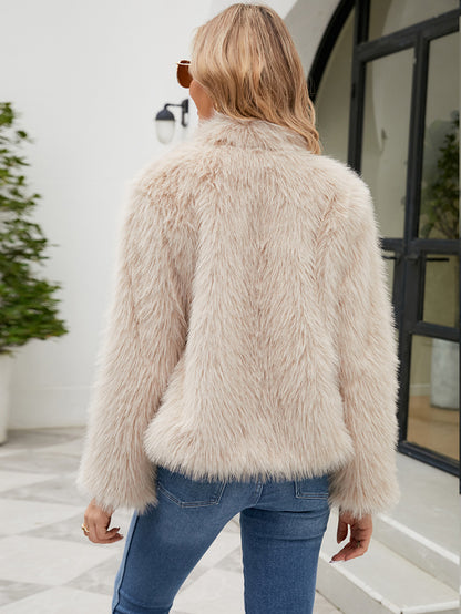 Woman wearing a fluffy beige jacket in an indoor setting