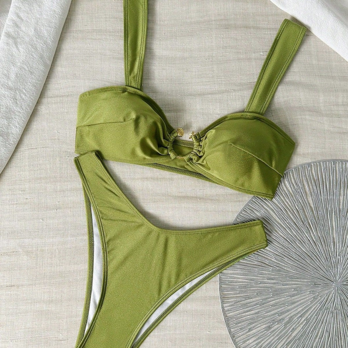 Green bikini set on a textured surface with a decorative fan