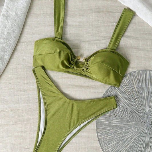 Green bikini set on a textured surface with a decorative fan