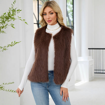 Woman wearing a brown fur vest over a white turtleneck and blue jeans indoors.