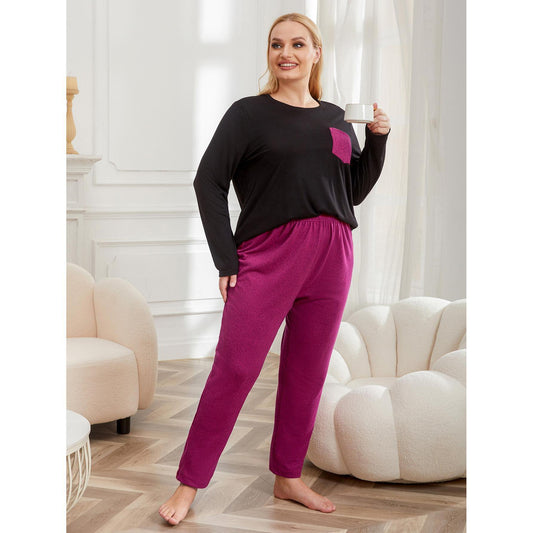 Woman wearing a black top and magenta pants holding a mug in a room with white walls and furniture.